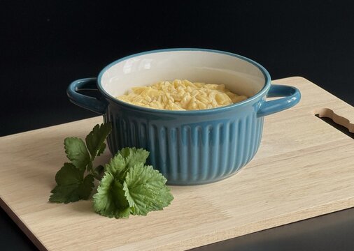 Mac and cheese in a blue bowl, standing on a wooden board