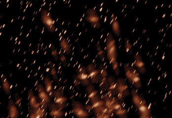 Close up of golden sparks and glittering particles scattered in a dark background, capturing a warm festive atmosphere, dynamic light showers, and dramatic texture for celebration visuals
