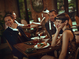 Stylish retro friends enjoying food, conversation, and warm evening atmosphere. Concept of restaurant promo, Christmas creatives, fashion-lifestyle visuals, and premium branding.