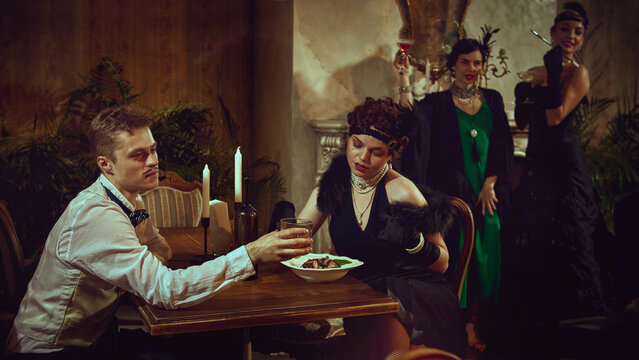 Vintage couple dining with emotional retro mood in elegant restaurant setting. Concept of romantic nightlife content, themed evenings, premium bar promos, fashion and lifestyle storytelling.