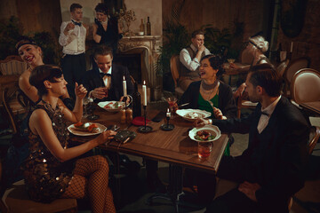 Retro dinner gathering with laughing friends enjoying elegant vintage restaurant evening. Concept of holiday event campaigns, luxury dining visuals, themed retro marketing, nightlife social content.