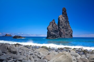 A rocky shoreline with a large rock formation in the distance