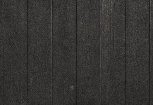 Close up of dark asphalt roof shingles showing granular texture and vertical seam lines, creating a repeating architectural pattern for construction and exterior design imagery