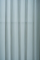 Obraz premium Sheer white curtains and a heavier, darker curtain partially drawn, allowing soft light to filter through.
