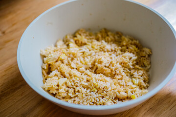 Close-up of a white bowl filled with golden, crunchy cereal on a wooden table.