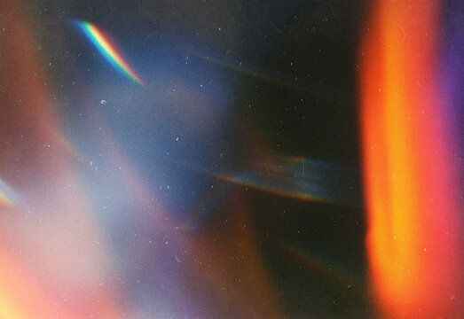 Abstract composition with vibrant light leaks and gradient streaks across a dark surface, blending warm orange and pink with cool blue and purple hues for a dreamy texture