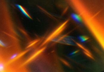 Abstract close up of shimmering orange light streaks and iridescent reflections across a dark textured backdrop, creating a warm, energetic composition for creative projects