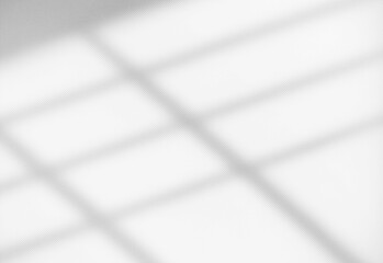 Abstract grayscale photograph of diagonal window shade shadows across a smooth white surface, forming geometric lines and gentle gradients that convey a minimal, modern design mood