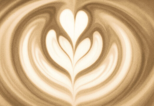 Close up of a creamy latte with heart leaf latte art swirling in warm caramel tones, smooth foam texture, crafted coffee beverage in a cozy cafe setting for a welcoming morning