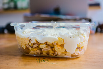Delicious food in a transparent container on a wooden table.