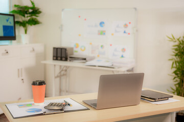 Businesswoman smiling while using laptop and talking on mobile phone at desk in office and at home or coffee shop.
