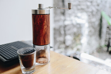 Manual coffee grinder with espresso shot on wooden table.