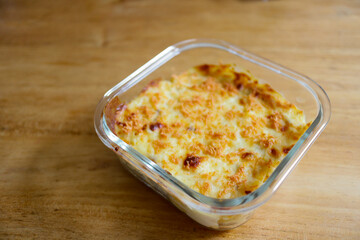 Golden Baked Pasta in Glass Dish on Wooden Table.