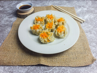 Shrimp and chicken dimsum served on a white plate with soy sauce on the side 