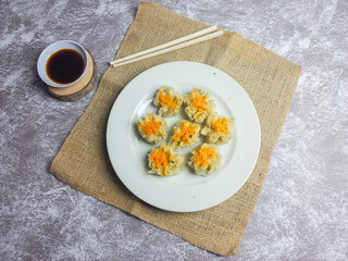 Shrimp and chicken dimsum served on a white plate with soy sauce on the side 