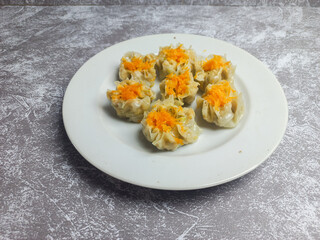 Shrimp and chicken dimsum served on a white plate with soy sauce on the side 