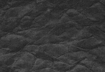 Close up of a dark textured surface with subtle grain, crinkles, and shadowed folds resembling rugged rock or coarse fabric, ideal as background for photography and design