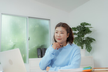 Businesswoman smiling while using laptop and talking on mobile phone at desk in office and at home or coffee shop.