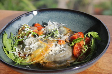 Handmade ravioli with cherry tomato sauce, parmesan, arugula, and edible flowers—an elegant, colorful, and flavorful Italian dish.
