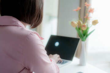 Businesswoman smiling while using laptop and talking on mobile phone at desk in office and at home or coffee shop.