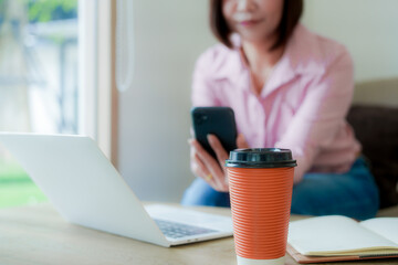 Businesswoman smiling while using laptop and talking on mobile phone at desk in office and at home or coffee shop.