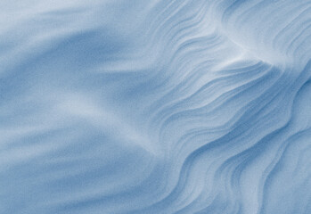 Close-up of wind-sculpted blue sand texture in a tranquil desert scene, highlighting soft ridges, fine grains, cool tones, abstract landscape, and tactile surface detail