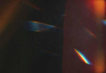 Abstract night scene featuring colorful light leaks, speckled grain, and soft lens flares across a dark textured background, creating a dramatic texture for design projects