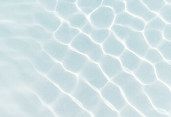 Close up of a pale blue water surface with sunlit ripples creating geometric patterns, providing a refreshing natural texture ideal for background design and wellness visuals