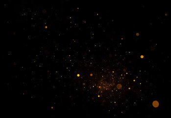 Abstract golden bokeh particles scattered across a deep black background, creating festive cinematic glow with luminous specks and shimmering dust texture for luxury branding