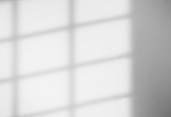 Soft natural light filters through a striped window blind, casting geometric shadows across a quiet minimalist interior, creating a calm, productive atmosphere for work or study.