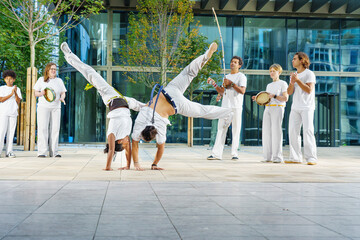 A group of sporty people of different ages training capoeira in a big city