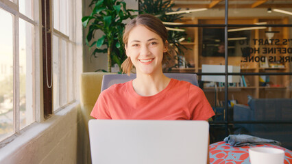 Portrait Of Young Smiling Businessman Working On Laptop In Modern Office