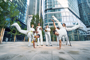 A group of sporty people of different ages training capoeira in a big city