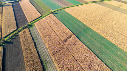 Aerial view of diverse agricultural fields showcasing various crops and brown, green patterns under...