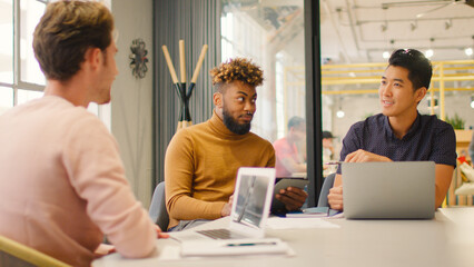 Young Multi Cultural Male Business Team Meeting Around Table In Modern Office