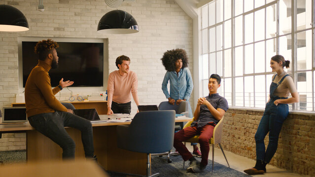 Young Multi Cultural Business Team Meeting Around Desk In Modern Office