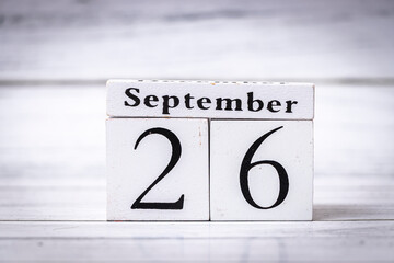 A wooden calendar block displays September 26, symbolizing the importance of dates in organizing time and planning events in both personal and professional contexts.