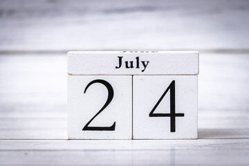 A wooden calendar block displays the date July 24, representing time management and organization. Ideal for promoting productivity or event planning.