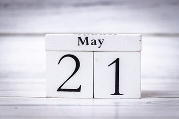 A wooden calendar displays May 21, set against a light wooden background. This image captures the essence of time, schedules, and organization, ideal for various editorial uses.