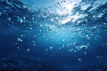 Underwater view shows bubbles rising to sunlit surface, deep blue hue