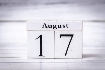 A wooden block calendar displaying the date August 17. The background is softly blurred, emphasizing the calendar. Ideal for seasonal themes or event planning.