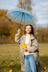 Happy woman with umbrella enjoying autumn sunlight and freedom in the park