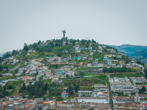 Aerial view of El Panecillo hill crowned by the Virgin of Quito statue, a tapestry of homes clinging to its slopes, , Quito, Ecuador.