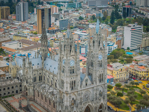 Aerial view of the grand Basilica del Voto Nacional rises in ornate gothic splendor, its spires piercing the sky amidst Quito's urban tapestry, Quito, Ecuador.