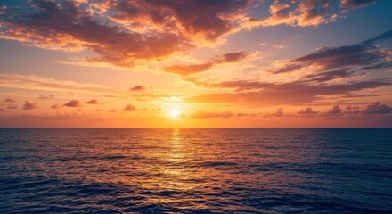 Fototapeta premium A vibrant sunset over a tranquil ocean. Golden hues paint the sky, clouds, and water. Sun near horizon