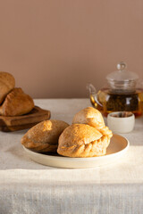 Homemade baked pies (pirozhki) with cabbage on a tray with tea and sugar. Traditional Russian, Ukrainian and Belarussian cuisine. Vertical orientation.
