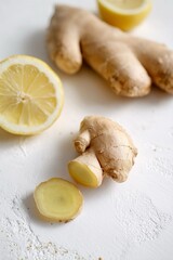 Composizione di zenzero fresco e spicchi di limone, disposti su uno sfondo bianco, suggerendo un'atmosfera di salute, benessere e semplicità.