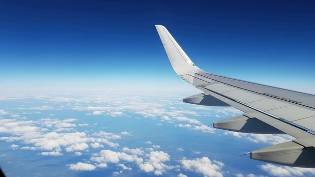 Soaring above fluffy clouds on a bright sunny day, airplane wing guides journey through endless blue sky 4k high quality footage