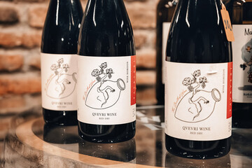 Naklejka premium 31 October 2025, Tbilisi Wine museum, Georgia: Qvevri wine bottles, displaying graphic labels with a traditional clay vessel