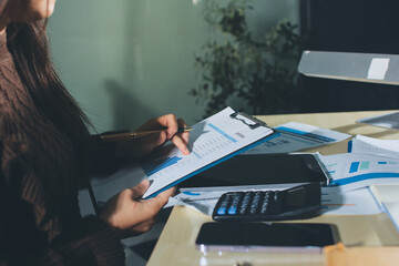 Close-up of businessman's hands making notes, mobiles, chart, desk, office